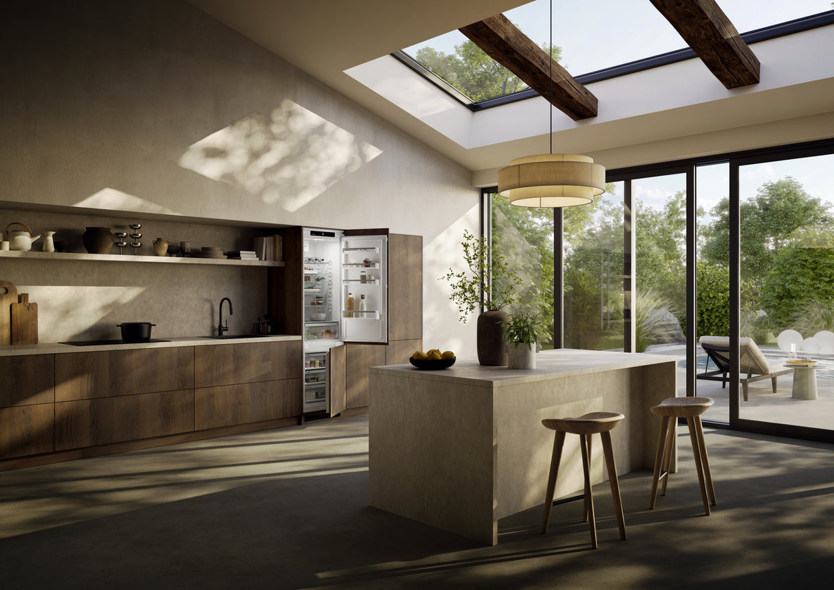 Cuisine en bois et béton baignée de lumière, avec combiné Liebherr ouvert intégré dans les colonnes