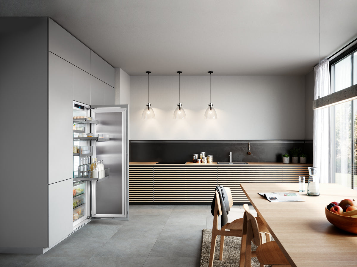 Réfrigérateur encastrable Liebherr ouvert dans une cuisine grise avec table en bois