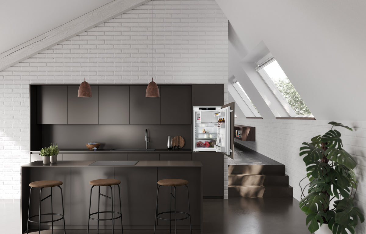 Réfrigérateur encastrable Liebherr ouvert dans une cuisine noire sous combles
