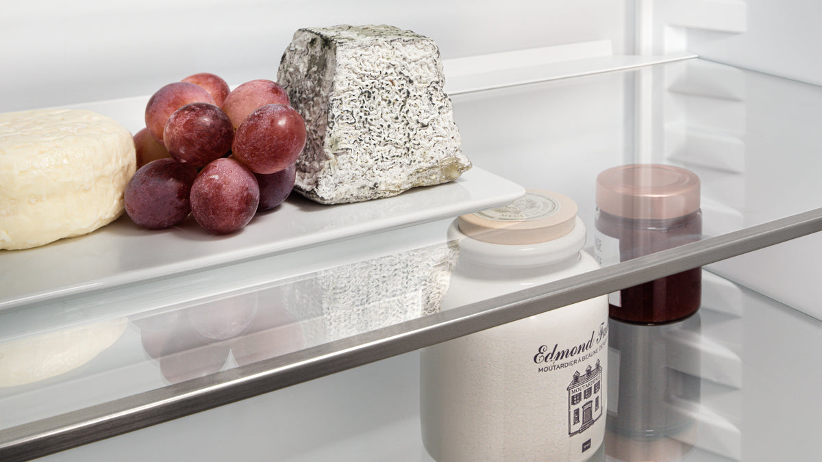 Fromages et raisins sur une clayette en verre d’un réfrigérateur Liebherr