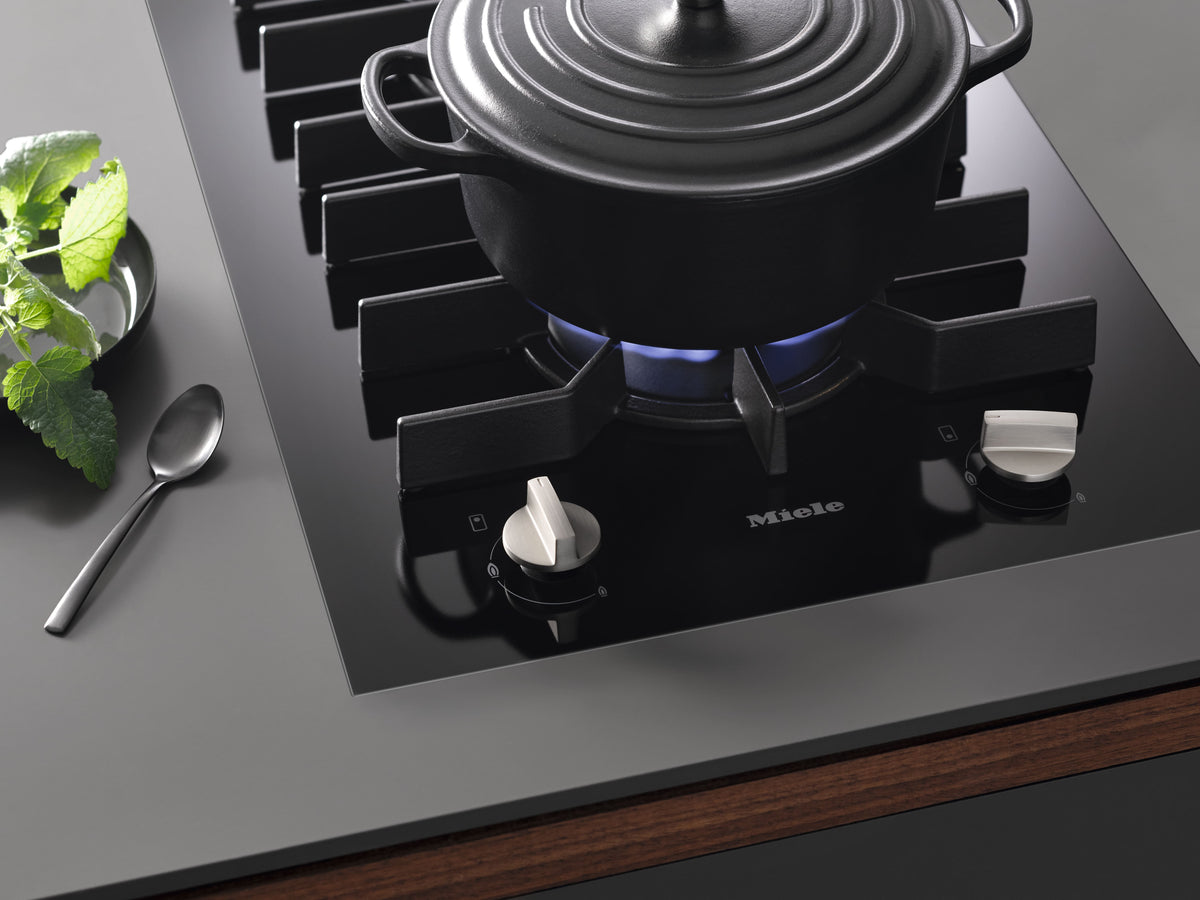 Cocotte noire sur le brûleur allumé du domino gaz SmartLine Miele CS 7102-1 FL