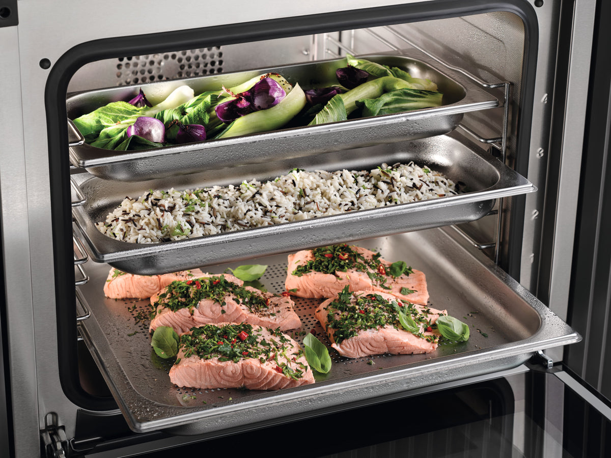 Saumon, riz et légumes cuits à la vapeur sur plusieurs niveaux dans un four vapeur combiné Miele ouvert