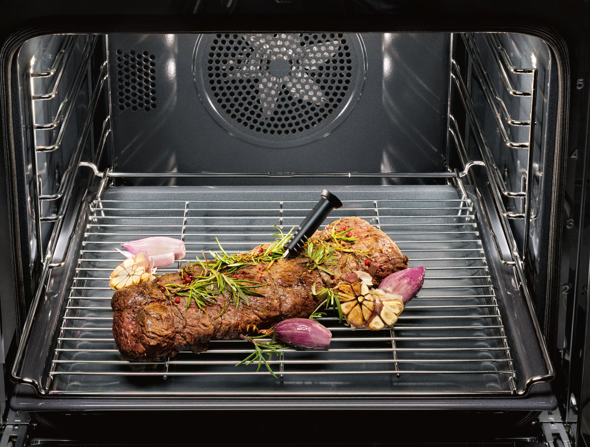 Thermosonde sans fil plantée dans une pièce de viande sur la grille d’un four Miele