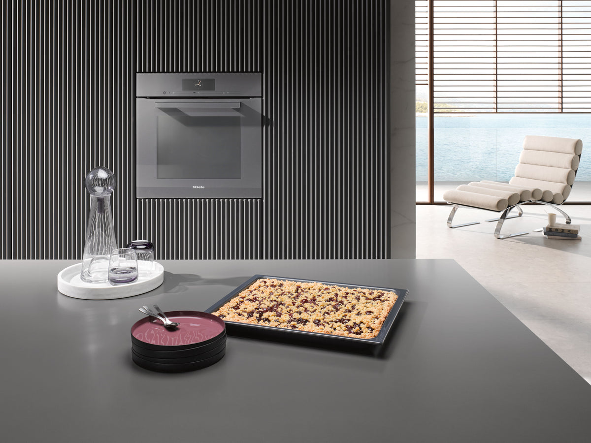 Four Miele gris graphite encastré dans un mur cannelé, gâteau sur le plan de travail