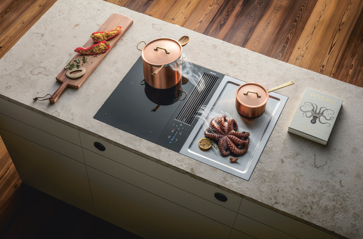 Dispositif aspirant BORA Classic 2.0 entre une table induction et un teppanyaki, dans un îlot en pierre