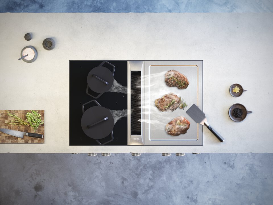 Viande grillée sur le teppanyaki BORA Professional 3.0 à côté d’une table à induction mate, vue de dessus