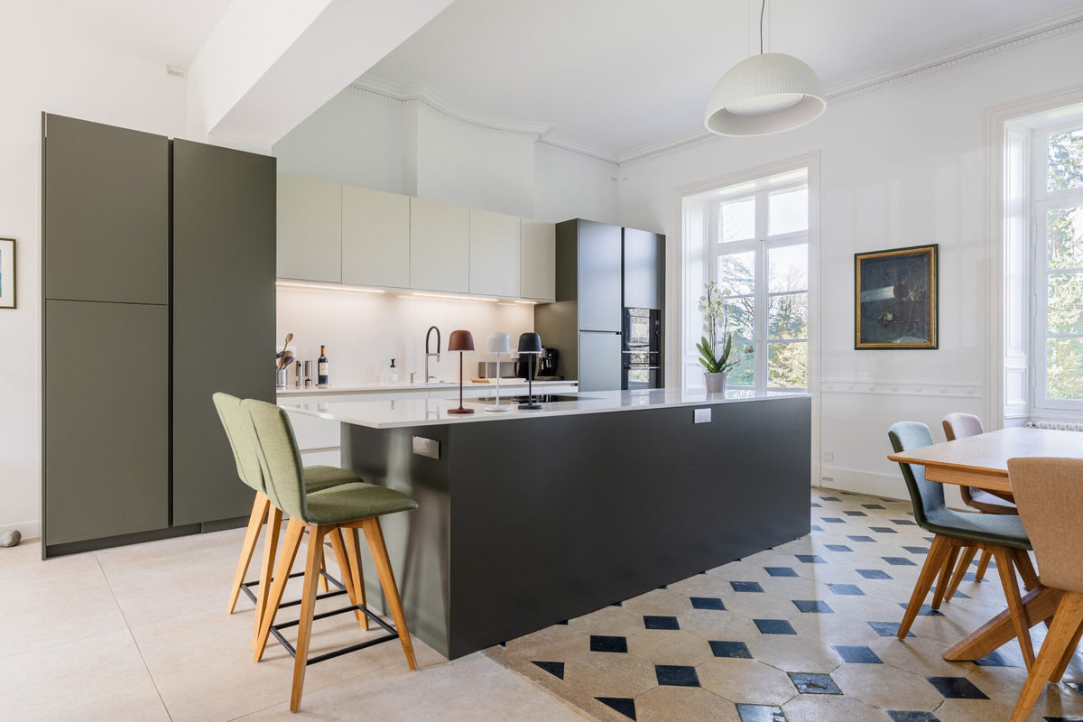 Cuisine vert olive avec îlot, tabourets et salle à manger dans une demeure ancienne