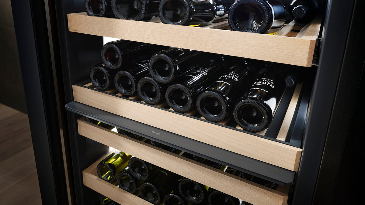 Bouteilles couchées sur des clayettes en bois d’une cave à vin Liebherr