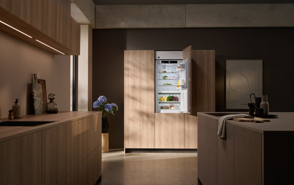 Combiné réfrigérateur-congélateur encastrable Liebherr ouvert dans une cuisine en bois sombre