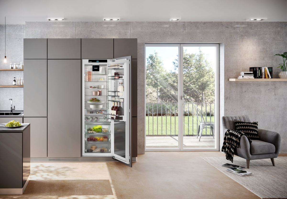 Réfrigérateur Liebherr ouvert dans une colonne de cuisine grise, face au jardin