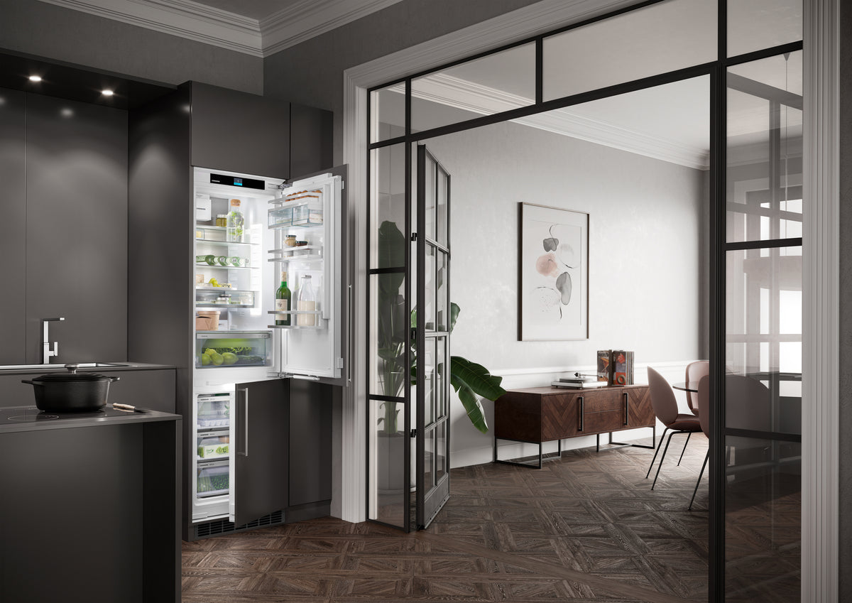 Combiné encastrable Liebherr ouvert dans une cuisine sombre, derrière une verrière