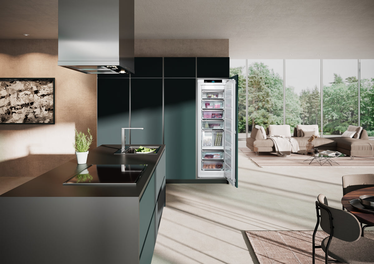 Congélateur Liebherr ouvert dans une colonne vert sombre, cuisine ouverte sur un séjour lumineux