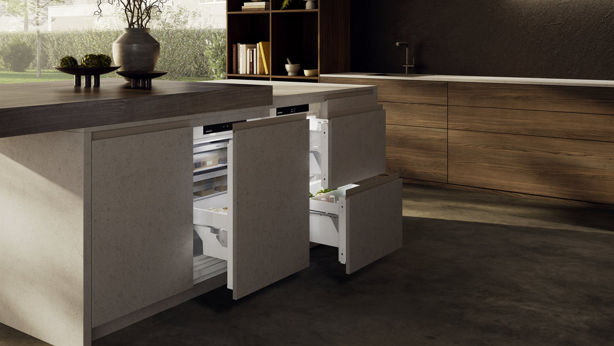 Tiroirs de congélation Liebherr ouverts sous un îlot de cuisine en bois