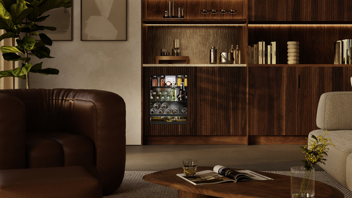 Réfrigérateur à boissons Liebherr intégré dans une bibliothèque en bois, face à un fauteuil en cuir