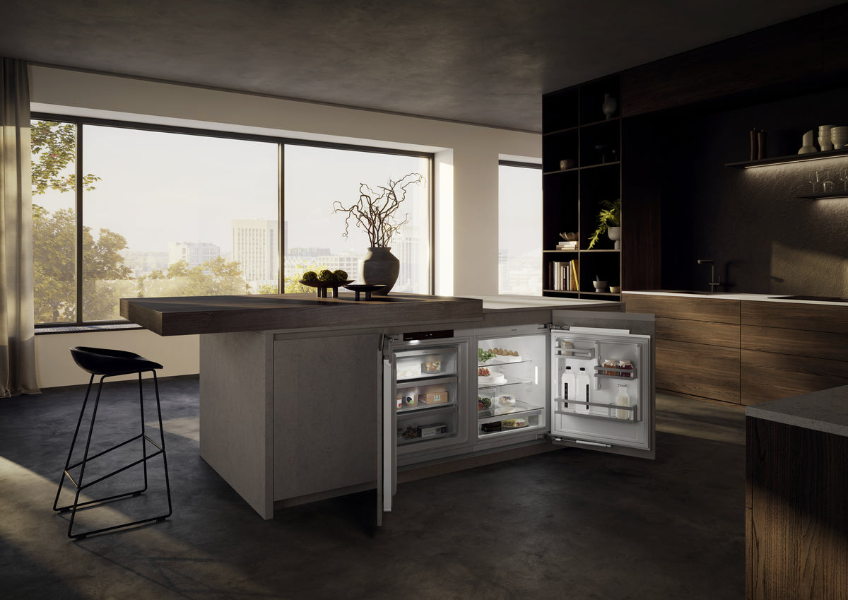 Réfrigérateur sous plan Liebherr ouvert sous l’îlot d’une cuisine aux tons sombres
