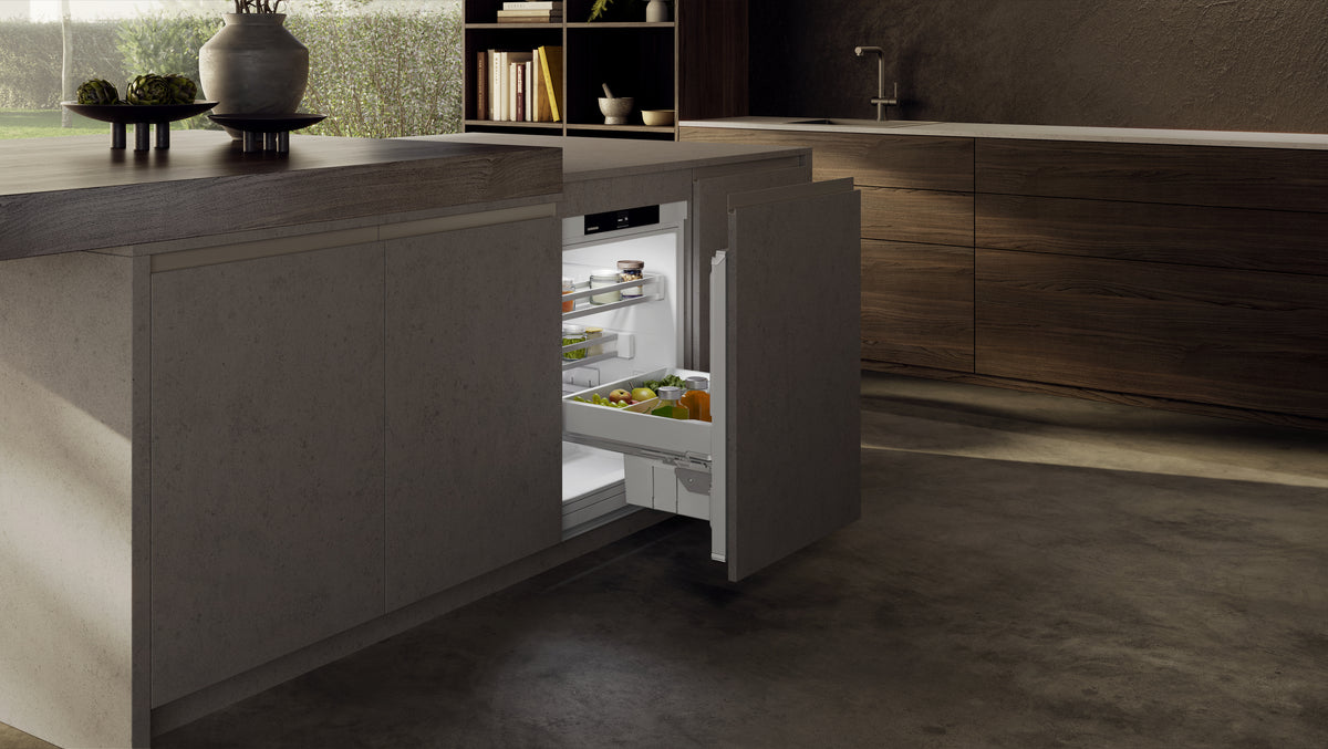 Réfrigérateur sous plan Liebherr à tiroir coulissant ouvert dans un îlot de cuisine sombre