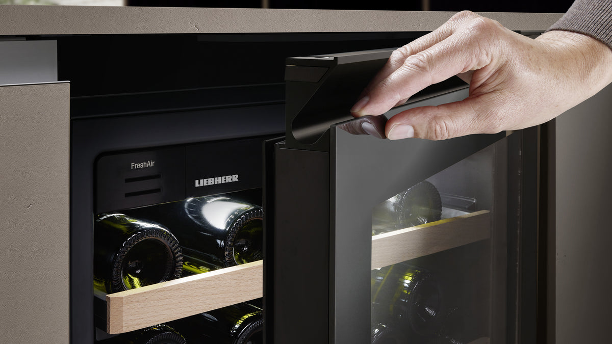 Main ouvrant une cave à vin Liebherr GlassBlack par sa poignée encastrée horizontale