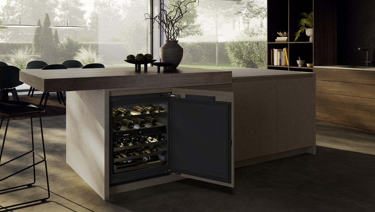 Cave à vin sous plan Liebherr ouverte sous un îlot de cuisine en bois
