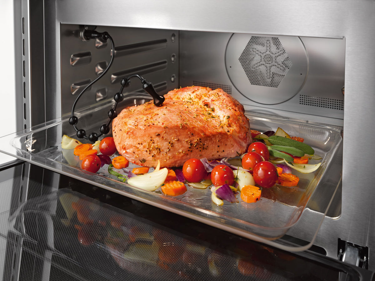Rôti et légumes dans un plat en verre avec thermosonde filaire, dans un four Miele combiné micro-ondes