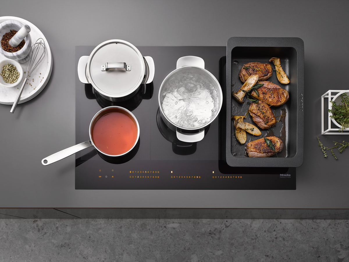 Casseroles et plat à rôtir sur une table de cuisson Miele, vue de dessus du pont PowerFlex